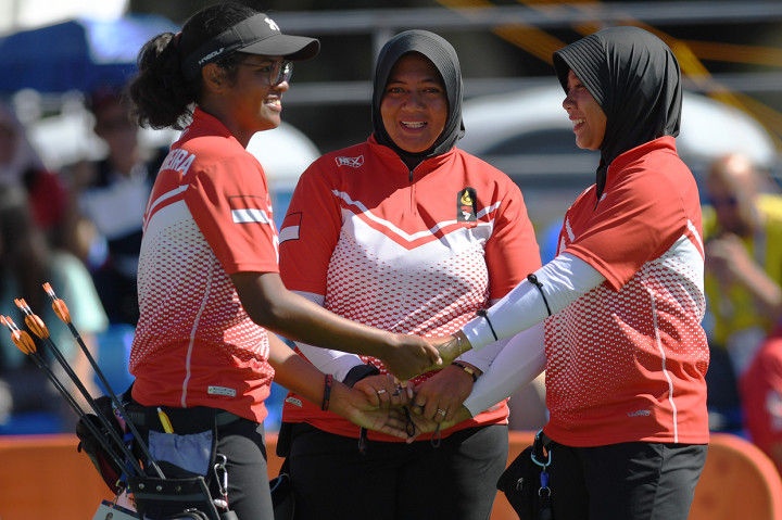 Tim panahan putri Indonesia Triya Resky Adriyani (tengah) Sri Ranti (kanan), dan Yurike Nina Bonita Pereira berpegangan tangan saat meraih angka pada pertandingan Final Panahan Compound Tim Putri SEA Games ke-30 di Lapangan Parade Ground Clark Freeport, Filipina.
