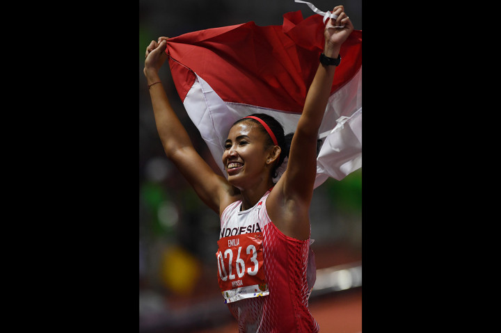 Pelari Indonesia Emilia Nova membentangkan Bendera Merah Putih setelah berhasil menyelesaikan Lomba Lari Gawang 100 Meter Putri SEA Games ke-30 di Stadion Atletik New Clark, Filipina.