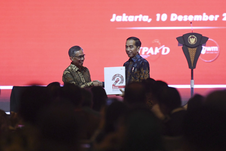 Ketua Dewan Komisioner Otoritas Jasa Keuangan (OJK) Wimboh Santoso (kiri) menyerahkan buku dua tahun Bank Wakaf Mikro (BWM) kepada Presiden Joko Widodo (kanan) saat Rapat Koordinasi Nasional Tim Percepatan Akses Keuangan Daerah (TPAKD) dan Silahturahmi Nasional Bank Wakaf Mikro 2019 di Jakarta.