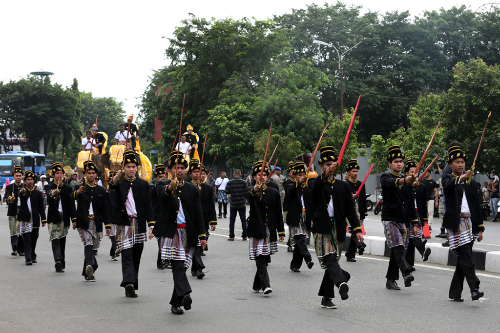 Warga memakai pakaian tradisional sambil membawa pedang saat mengikuti pawai pada karnaval budaya Koetaradja di Banda Aceh, Aceh.