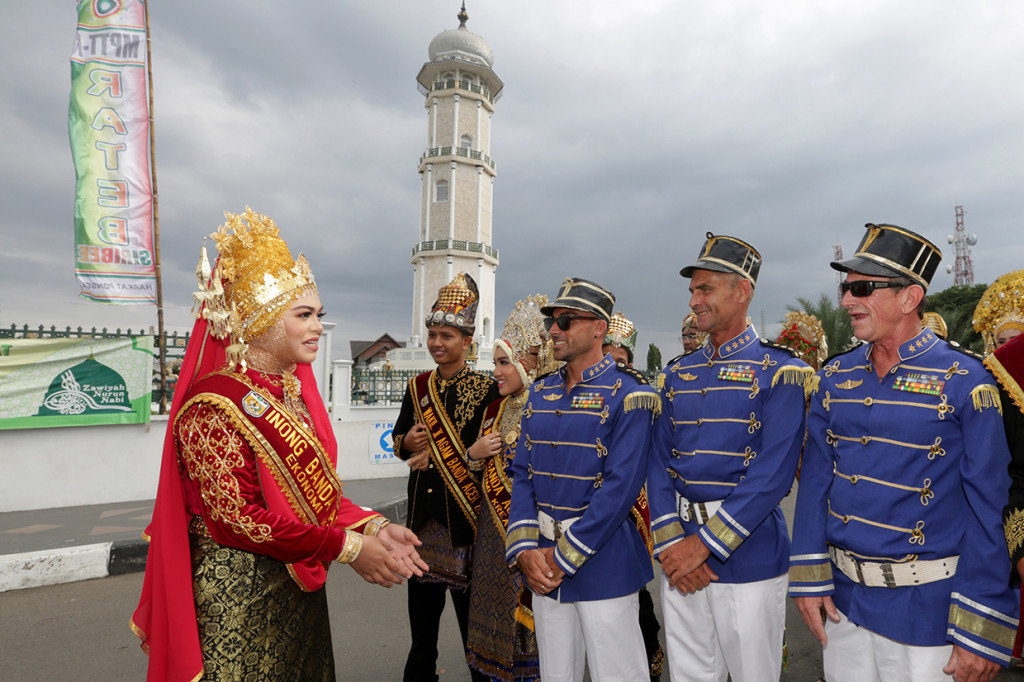 Inong wisata Kota Banda Aceh (kiri) berbincang dengan wisatawan asing yang mengikuti pawai pada karnaval budaya Koetaradja di Banda Aceh, Aceh. Karnaval ini selain untuk meningkatkan kunjungan wisatawan mancanegara juga bertujuan memperkenalkan adat istiadat dan budaya masyarakat Aceh serta keberagaman suku bangsa yang hidup rukun di Kota Banda Aceh. 
