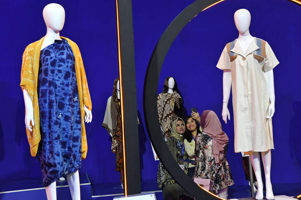 Pengunjung berswafoto dengan latar belakang baju batik yang dipamerkan dalam pameran 'UMKM Export BRILian Preneur 2019' di Jakarta Convention Center (JCC), Jakarta.