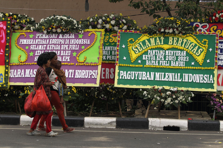 Warga melintas di antara karangan bunga ucapan selamat kepada pimpinan Komisi Pemberantasan Korupsi (KPK) periode 2019-2023 di depan Gedung Merah Putih KPK, Jakarta, Jumat, 20 Desember 2019.