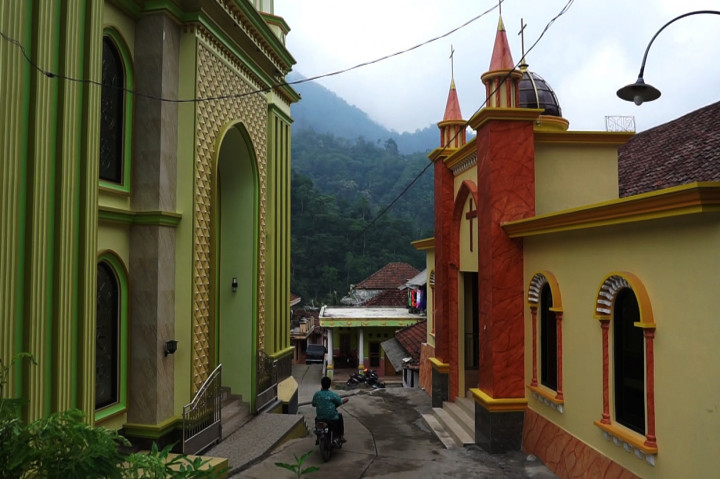 Dua bangunan itu hanya dipisahkan gang di tengah permukiman selebar 2,5 meter. Pintu masjid tepat berhadapan dengan pintu gereja.