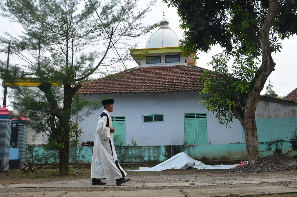 Pendeta Teguh Setyoadi berjalan dengan latar belakang Masjid Al Hidayah di Dusun Mutersari, Desa Ngrimbi, Kecamatan Bareng, Jombang, Jawa Timur.