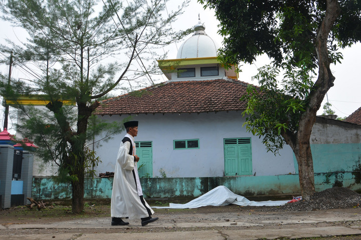 Pendeta Teguh Setyoadi berjalan dengan latar belakang Masjid Al Hidayah di Dusun Mutersari, Desa Ngrimbi, Kecamatan Bareng, Jombang, Jawa Timur.