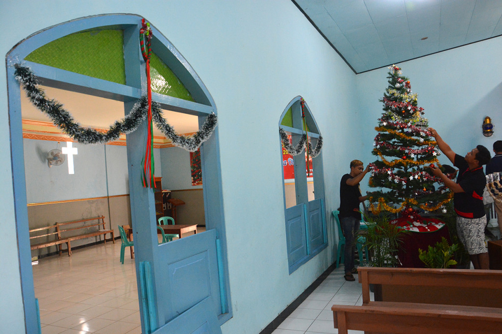Anggota Karang taruna Desa Ngrimbi membantu mendekor pohon Natal di Gereja Kristen Jawi Wetan (GKJW) Mutersari, Kecamatan Bareng, Jombang, Jawa Timur.
