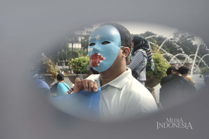 Warga mengenakan topeng bendera Turkestan Timur saat menggelar Aksi Save Uighur selama CFD Jakarta.