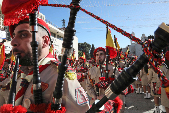 Warga Palestina berparade di Lapngan Manger di luar Gereja Kelahrian di Betlehem menjelang kedatangan Uskup Agung Pierbattista Pizzaballa, administrator apostolik Patriarkh Latin Yerusalem dan pejabat Katolik Roma paling senior di Timur Tengah. Dia akan memimpin misa tengah malam di Gereja Kelahiran, sementara Presiden Palestina Mahmud Abbas diharapkan hadir.