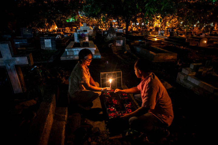 Warga keturunan Portugis menyalakan lilin saat melakukan ziarah ke makam anggota keluarga mereka pada malam Natal di kompleks Gereja Protestan Indonesia Barat (GPIB) Tugu, Semper Barat, Cilincing, Jakarta Utara, Selasa, 24 Desember 2019 malam.