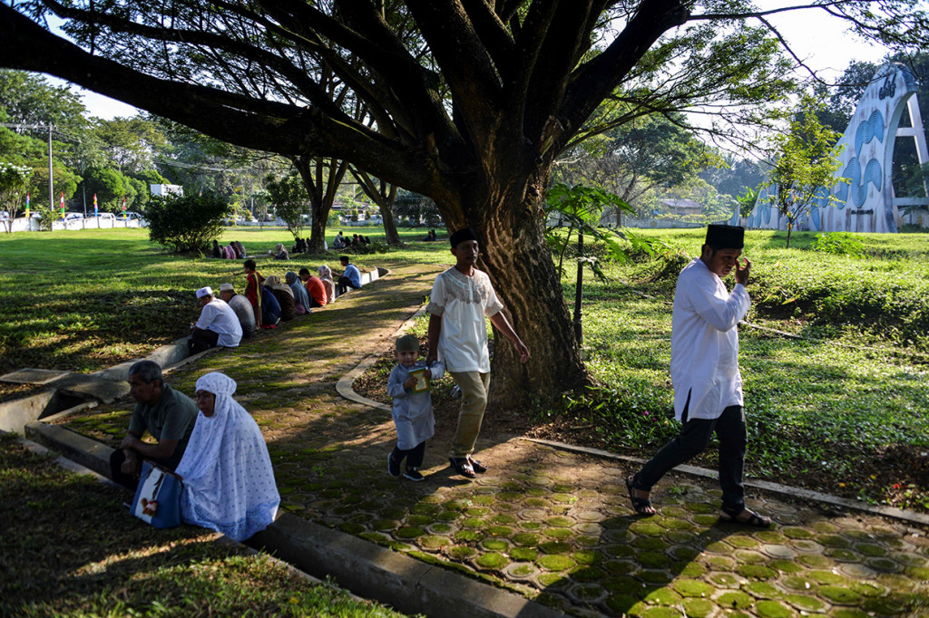 Keluarga berdoa dengan membaca surat Yassin saat berziarah pada peringatan 15 tahun bencana tsunami Aceh di kuburan massal korban, Desa Siron, Aceh Besar, Aceh, Kamis, 26 Desember 2019. AFP Photo/Chaideer Mahyuddin