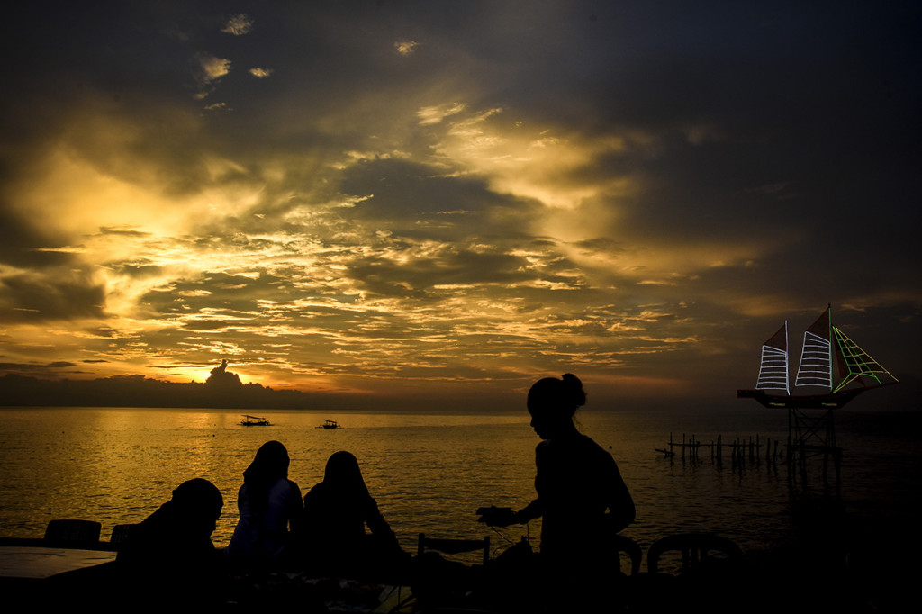 Sejumlah warga menikmati sunset atau matahari terbenam akhir tahun 2019 di Pantai Ampenan, Mataram, NTB. Antara Foto/Ahmad Subaidi