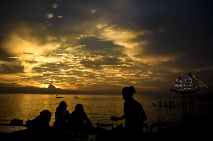 Sejumlah warga menikmati sunset atau matahari terbenam akhir tahun 2019 di Pantai Ampenan, Mataram, NTB. Antara Foto/Ahmad Subaidi