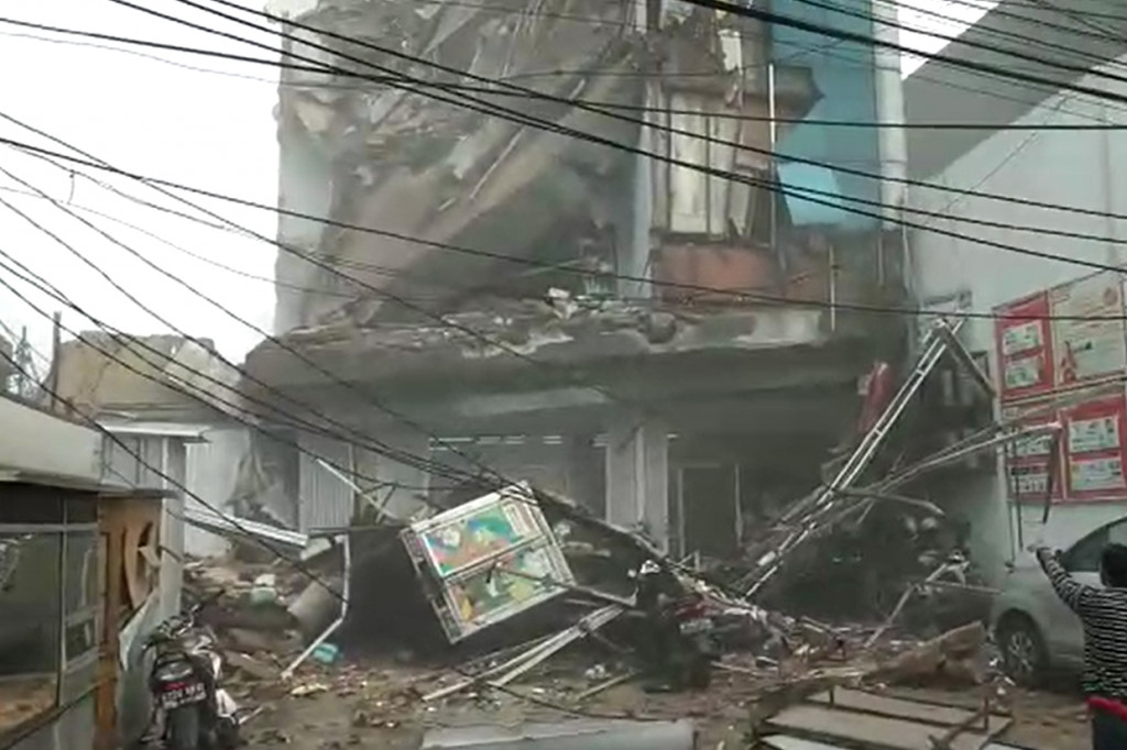 Terlihat bangunan itu menimpa minimarket Alfamart yang berada di lantai dasar.