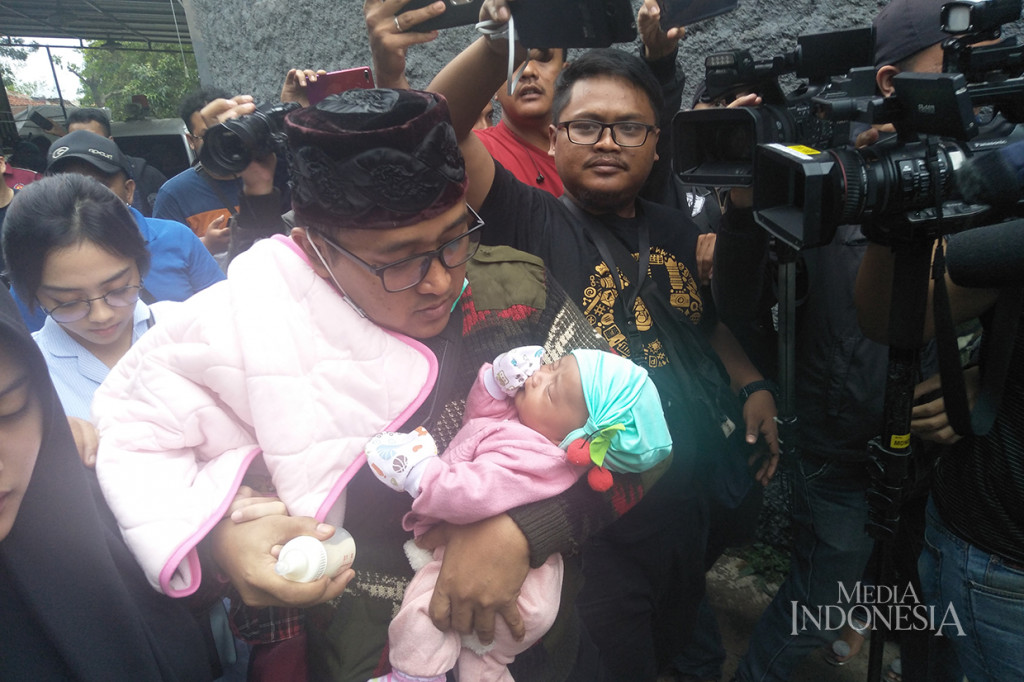 Suami Lina Jubaedah, Teddy, membawa anak mereka meninggalkan Tempat pemakaman keluarga Sekelimus, Bandung, Jawa Barat.