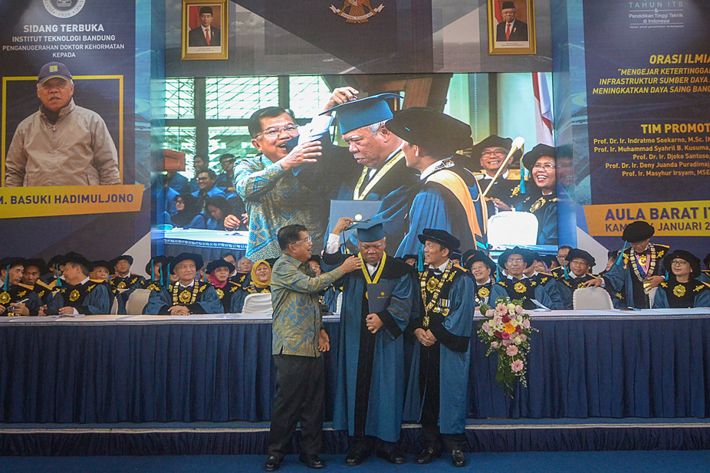 Wakil Presiden Indonesia ke-10 dan 12 Jusuf Kalla (kiri) merapikan topi toga Menteri Pekerjaan Umum dan Perumahan Rakyat (PUPR) Basuki Hadimuljono (tengah) disaksikan Rektor ITB Kadarsah Suryadi (kanan) saat penganugerahan Doktor Kehormatan atau Honoris Causa kepada Basuki Hadimuljono di Gedung Aula Barat ITB, Bandung, Jawa Barat. 