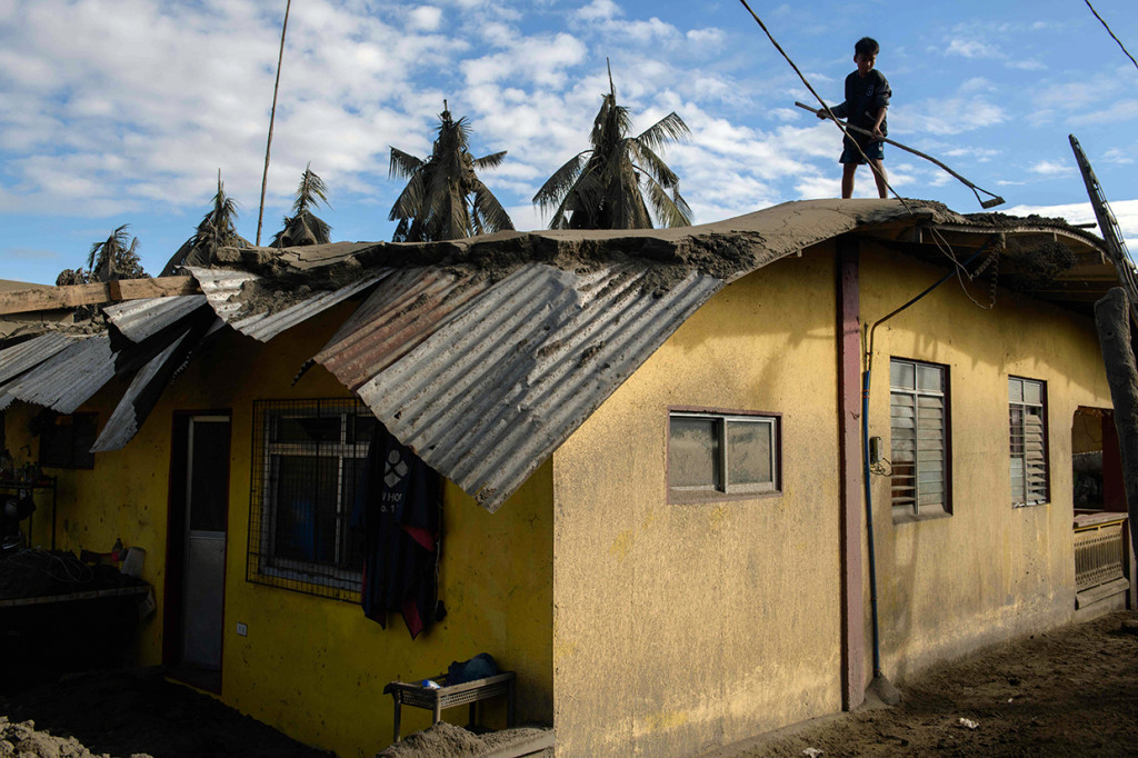 Seorang warga membersihkan abu tebal yang tersisa dari letusan gunung berapi Taal, dari atap rumahnya di Desa Buso-Buso dekat Laurel, Filipina, Jumat, 17 Januari 2020.
