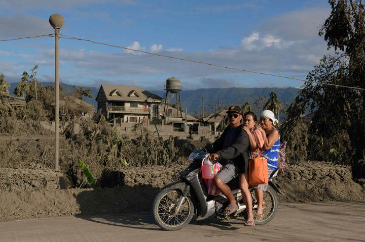 Deretan panjang mobil, truk, taksi motor yang membawa babi, anjing, pesawat televisi, kompor gas, dan kipas listrik, terlihat meninggalkan Agoncillo, di antara kota-kota yang diselimuti lapisan abu vulkanik yang tebal.