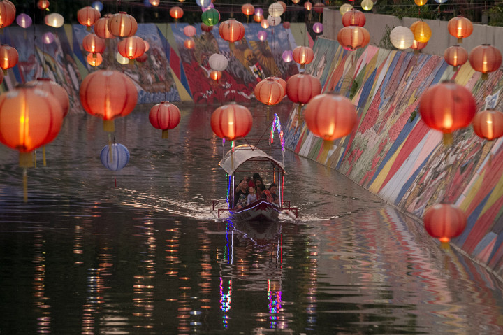 Warga menaiki perahu wisata Sungai Kali Pepe yang dihiasi lampion di Solo, Jawa Tengah, Jumat, 17 Januari 2020. 