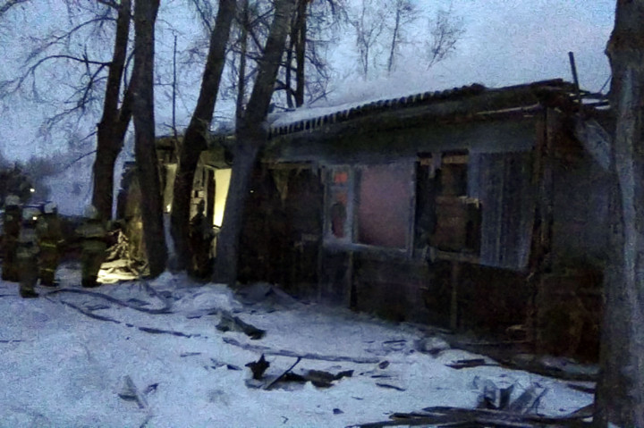 Petugas berusaha memadamkan api di lokasi kebakaran yang menghanguskan gubuk kayu di permukiman Prichulymsky di wilayah Tomsk, Rusia pada Selasa, 21 Januari 2020. 