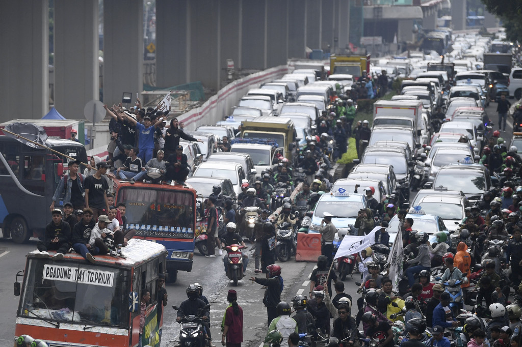 Warga Tanjung Priok menaiki atap metromini saat melakukan aksi di depan gedung Kemenkumham, Jakarta.