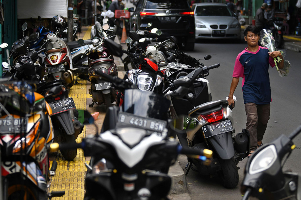 Warga berjalan di badan jalan raya karena trotoar yang menjadi haknya ditempati parkir liar sepeda motor di Jalan Sulaiman, Rawa Belong, Jakarta Barat, DKI Jakarta, Rabu, 22 Januari 2020.