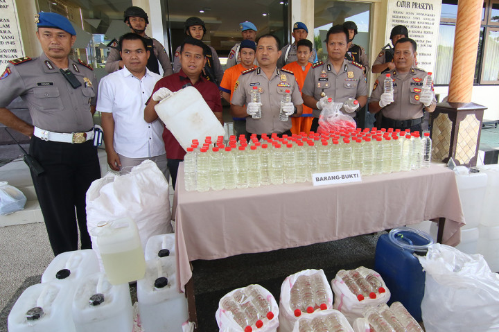 Kapolresta Banyuwangi Kombes Pol Arman Asmara Syarifudin (tengah) menunjukan hasil ungkap produksi minuman keras oplosan di Polresta Banyuwangi, Jawa Timur. Satgas Garda Blambangan Polresta Banyuwangi berhasil mengungkap produksi miras dari bahan air sumur dioplos dengan etanol yang dapat membahayakan kesehatan. 