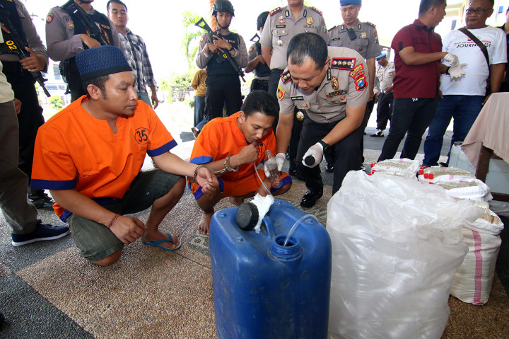 Kapolresta Banyuwangi Kombes Pol Arman Asmara Syarifudin (kanan) melihat cara tersangka memproduksi miniman keras oplosan di Polresta, Banyuwangi, Jawa Timur.
