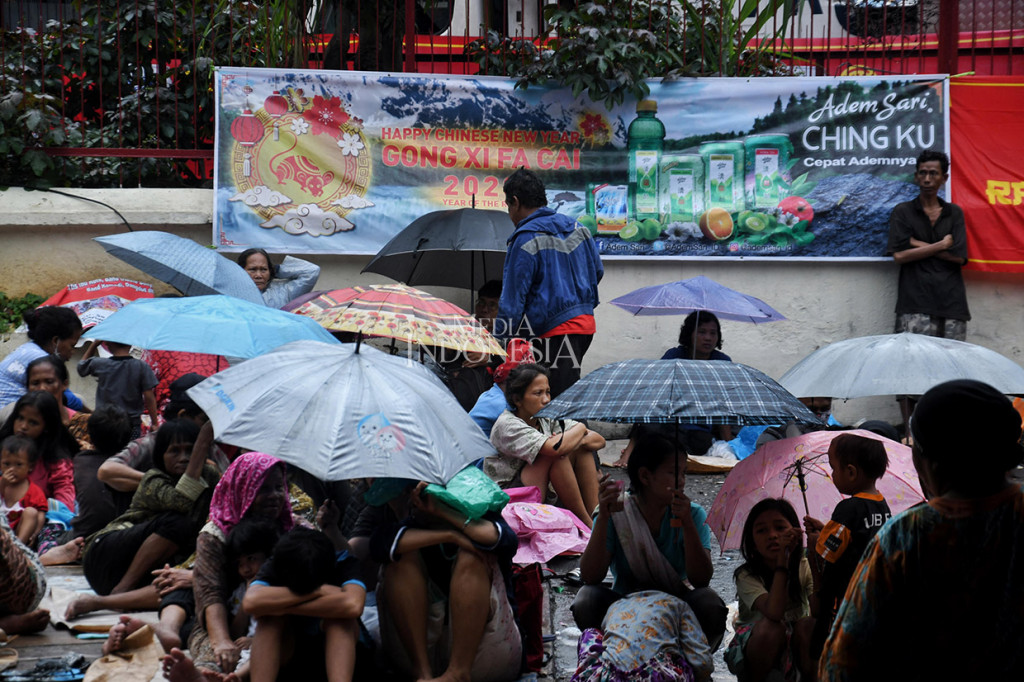 Karena hujan, sebagian pengemis musiman menggunakan payung dan jas hujan, serta duduk selonjoran menggunakan kardus. 