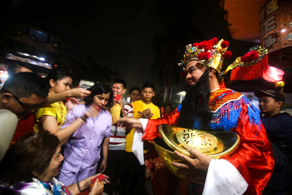 Pengurus wihara yang berdandan ala Dewa Uang Cai Shen membagikan angpao kepada warga yang sembahyang di Wihara Boen San Bio, Pasar Baru, Kota Tangerang, Jumat, 24 Januari 2020. 
