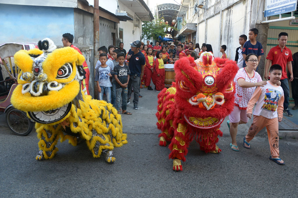 Warga menyaksikan atraksi barongsai berkeliling pasar di Peunayung, Banda Aceh, Aceh, Sabtu, 25 Januari 2020. ANTARA FOTO/Ampelsa