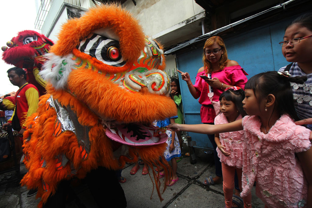Warga memberi angpao kepada pemain barongsai yang beratraksi di kampung pecinan Tambak Bayan, Surabaya, Jawa Timur. ANTARA FOTO/Didik Suhartono