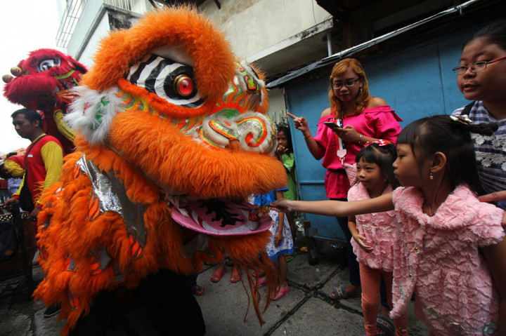 Warga memberi angpao kepada pemain barongsai yang beratraksi di kampung pecinan Tambak Bayan, Surabaya, Jawa Timur. ANTARA FOTO/Didik Suhartono