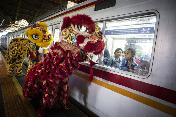 Penumpang KRL menyaksikan aksi Barongsai di peron Stasiun Gambir, Jakarta. ANTARA FOTO/Aprillio Akbar