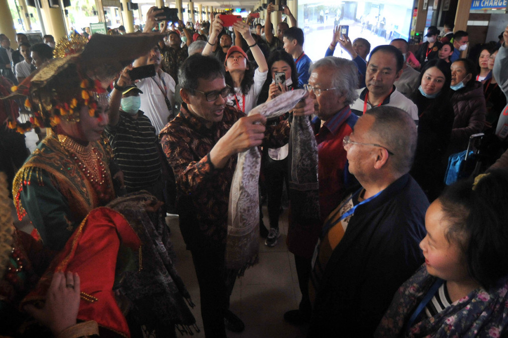 Gubernur Sumatera Barat Irwan Prayitno (kedua kiri) mengalungkan kain kepada salah satu wisatawan asal Tiongkok saat penyambutan di Bandara Internasional Minangkabau (BIM), Padangpariaman, Sumatera Barat, Minggu, 26 Januari 2020. 