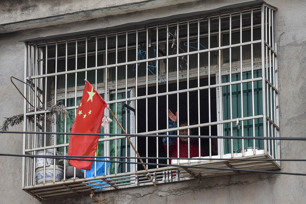 Seorang warga melambaikan tangan dari rumah mereka di sebuah lingkungan di pinggiran Wuhan di Provinsi Hubei.