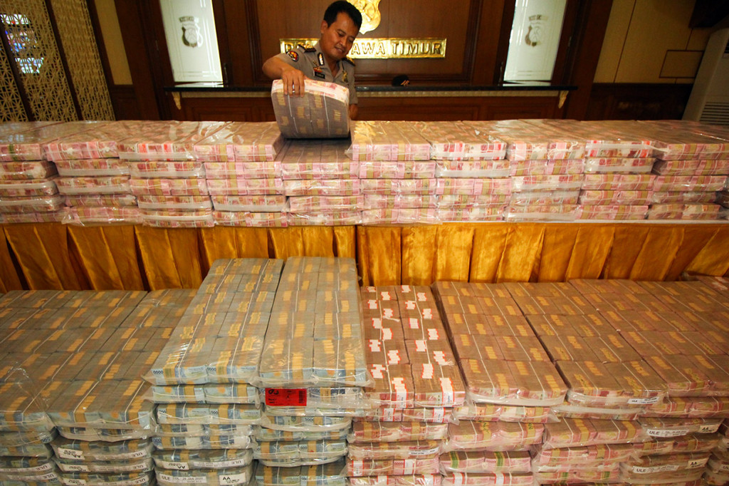 Polisi menata barang bukti uang tunai miliaran rupiah kasus dugaan investasi ilegal 'MeMiles' di Polda Jawa Timur, Surabaya, Jawa Timur, Selasa, 28 Januari 2020. 