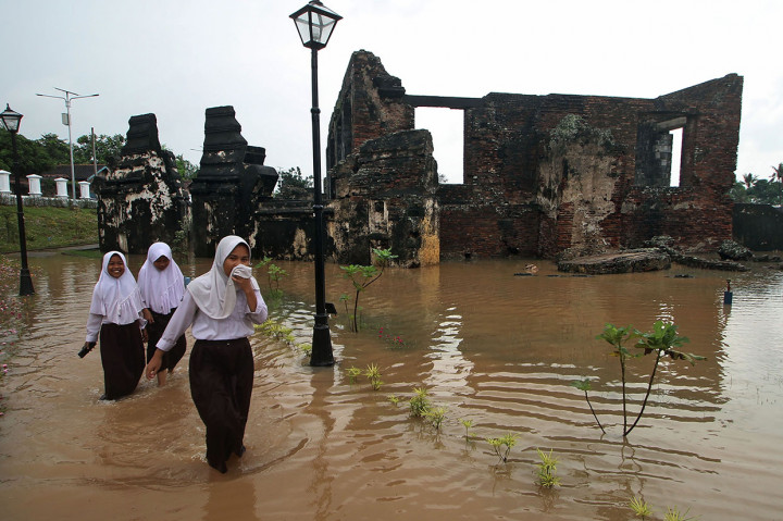 Sejumlah anak melintasi genangan air di area situs cagar budaya Keraton Kaibon yang terendam banjir di Kasemen, Serang, Banten, Selasa, 4 Febriari 2020.