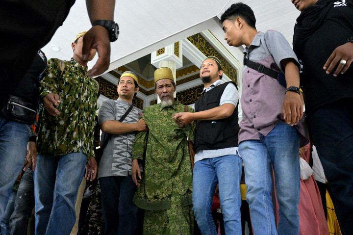 Pemimpin aliran kepercayaan tarekat Tajul Al Khalwatiyah Puang Lalang (tengah) dikawal pengikutnya saat akan melakukan kesepakatan perdamaian dengan Majelis Ulama Indonesia (MUI) Gowa di Masjid Agung Syekh Yusuf, Kabupaten Gowa, Sulawesi Selatan.