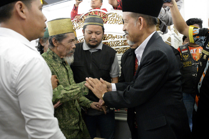 Pemimpin aliran kepercayaan tarekat Tajul Al Khalwatiyah Puang Lalang (kedua kiri) bersalaman dengan Ketua Majelis Ulama Indonesia (MUI) Gowa Abu Bakar Paka (kanan) saat melakukan kesepakatan perdamaian di Masjid Agung Syekh Yusuf, Kabupaten Gowa, Sulawesi Selatan.
