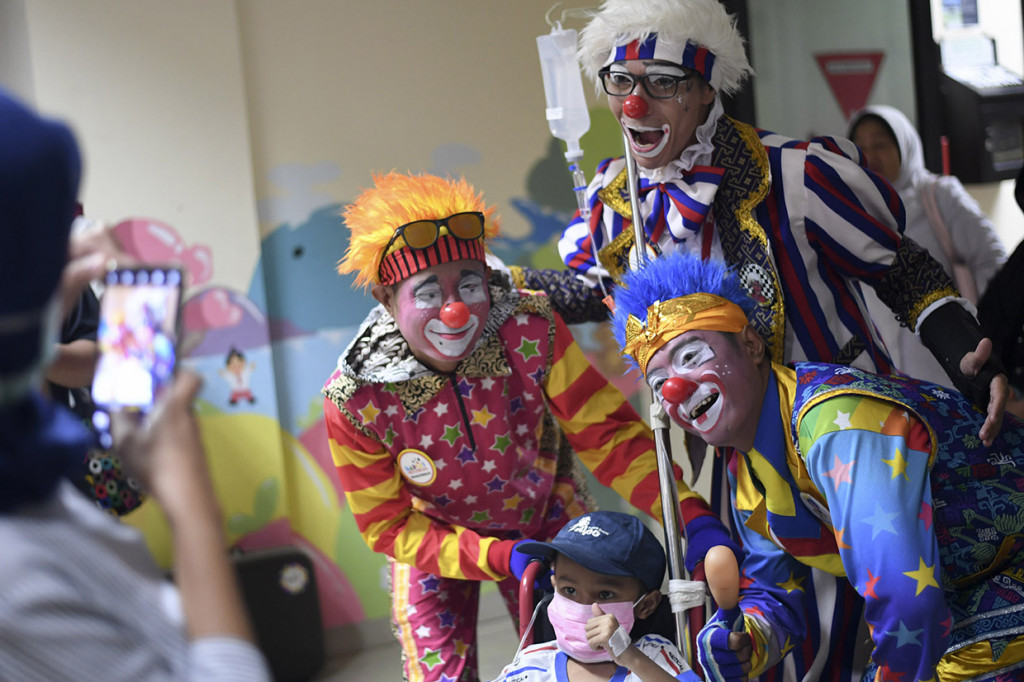 Tiga badut yang tergabung dalam Aku Badut Indonesia (ABI) berfoto dengan pasien saat menghibur anak yang dirawat di salah satu rumah sakit di Jakarta.