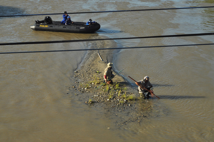 Petugas menunggu buaya liar yang terjerat ban sepeda motor muncul ke permukaan air di Sungai Palu, di Palu, Sulawesi Tengah, Kamis, 6 Februari 2020.