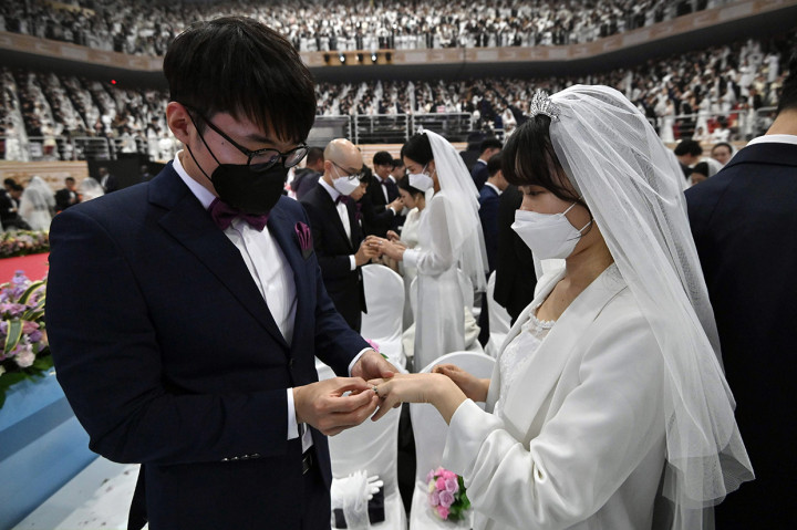 Pasangan pengantin mengenakan masker saat pelaksanakan penikahan di Cheongshim Peace World Center, Gapyeong, Korea Selatan, Jumat, 7 Februari 2020.