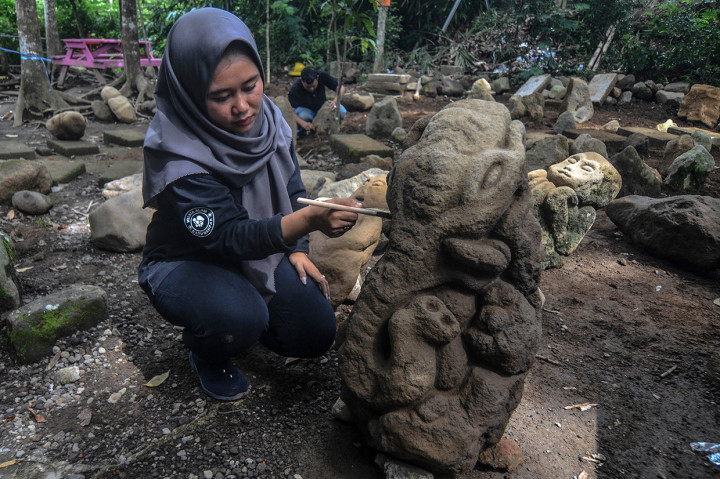 Petugas objek wisata membersihkan patung batu kuno di kawasan objek wisata batu Mahpar, di Desa Linggawangi, Kabupaten Tasikmalaya, Jawa Barat, Selasa, 11 Februari 2020.