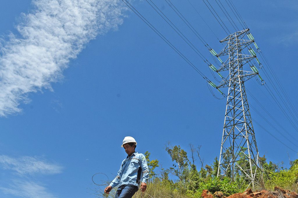 Pekerja melintas di dekat salah satu tower Transmisi Line 150 kV Malili (Sulawesi Selatan)-Lasusua (Sulawesi Tenggara) di Lasusua, Kabupaten Kolaka Utara, Sulawesi Tenggara. 