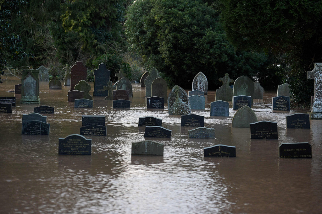 Air banjir mengelilingi batu-batu nisan di sebuah kuburan di Tenbury Wells. AFP Photo/Oli Scarff