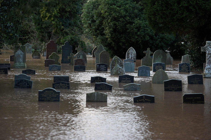 Air banjir mengelilingi batu-batu nisan di sebuah kuburan di Tenbury Wells. AFP Photo/Oli Scarff