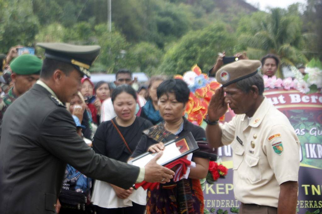 Kasrem 181/PVT, Kolonel Inf. Haryanto (kiri) saat menyerahkan bendera merah putih dan foto pada orang tua (kanan) Sertu Anumerta, Ikrar Setya Nainggolan, usai pemakaman di Taman Makam Pahlawan (TMP) Tri Jaya Sakti, Kota Sorong, Papua Barat.