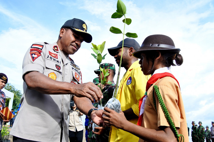 Wakapolda NTT Brigjen Johni Asadoma secara simbolik memberikan bibit mangrove kepada seorang pelajar di pesisir pantai Sulamanda saat kegiatan Polri Peduli Lingkungan, di Kupang, NTT. Sebanyak 10 ribu bibit mangrove ditanam di pesisir pantai Sulamanda untuk mencegah abrasi di pantai tersebut. ANTARA FOTO/Kornelis Kaha
