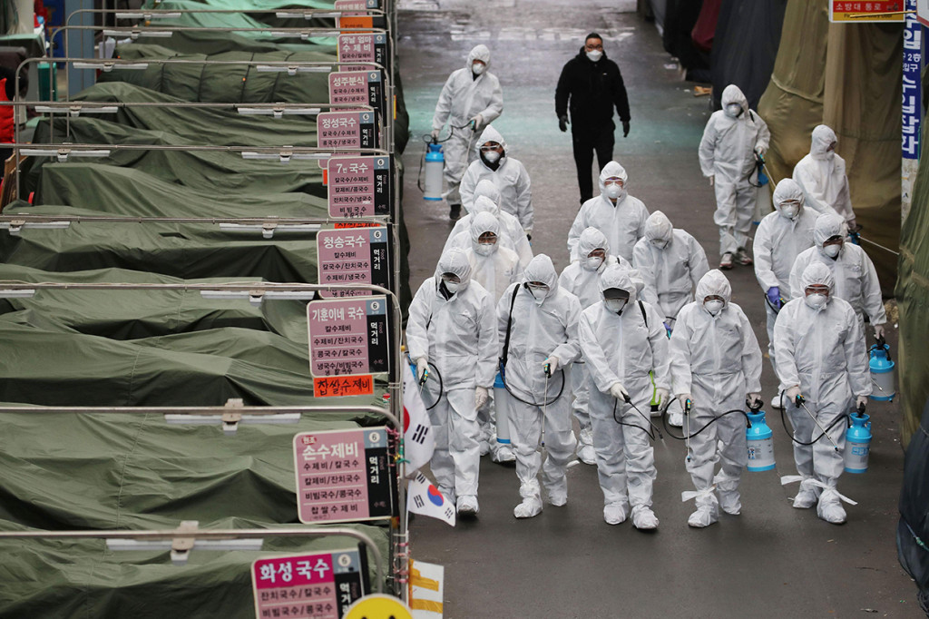 Petugas menyemprotkan disinfektan di depan sekte Gereja Sincheonji di Daegu yang menjadi lokasi penyebaran virus corona terbesar di Korsel. AFP Photo/Yonhap